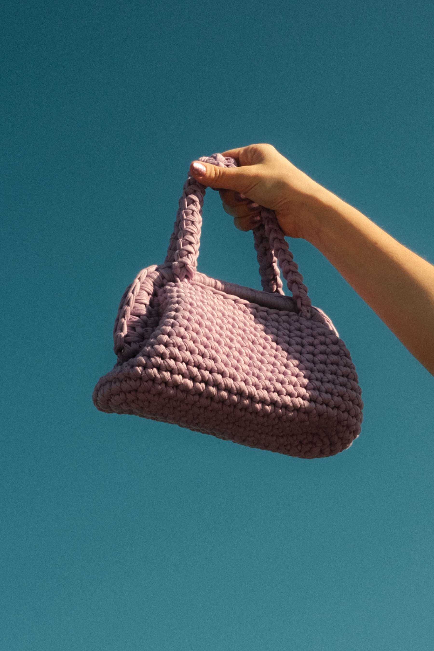 Borsa realizzata a mano tenuta in alto su sfondo azzurro